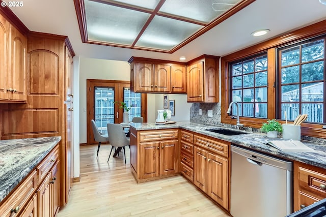 kitchen with stainless steel dishwasher, sink, a wealth of natural light, and light hardwood / wood-style flooring