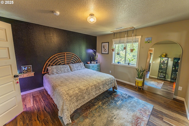 9511 NE 73rd St, Vancouver, WA 98662 - bedroom featuring a textured ceiling, an accent wall, wood finished floors, and arched walkways