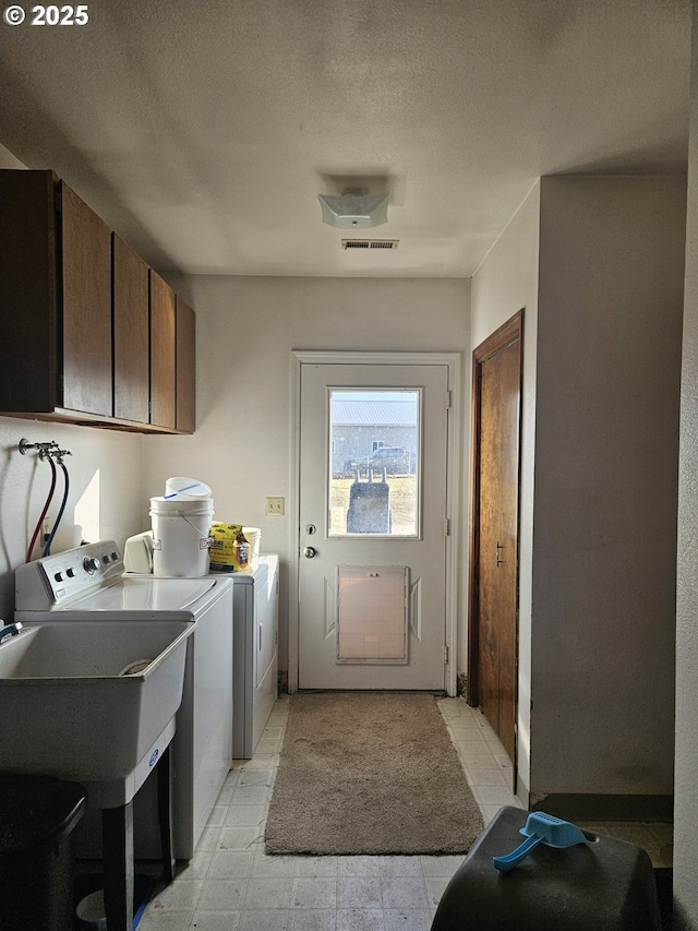 laundry room featuring washer and clothes dryer, cabinets, a textured ceiling, and sink