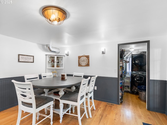 dining space with stacked washing maching and dryer and light hardwood / wood-style floors