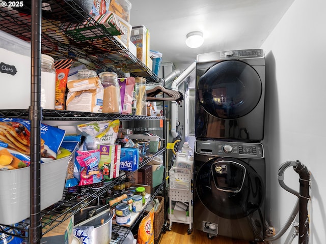 clothes washing area featuring hardwood / wood-style floors and stacked washing maching and dryer