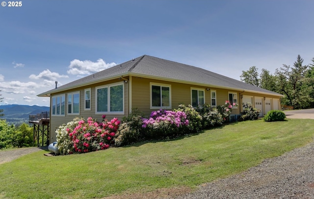 view of side of property with a yard, a garage, and a mountain view