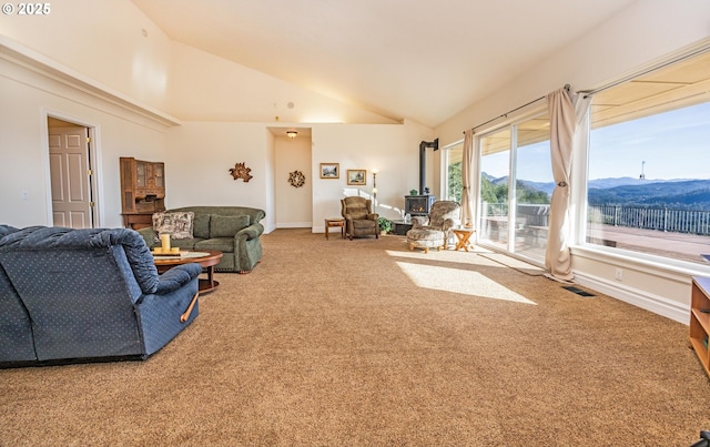 living room featuring high vaulted ceiling, a mountain view, carpet floors, and a wood stove