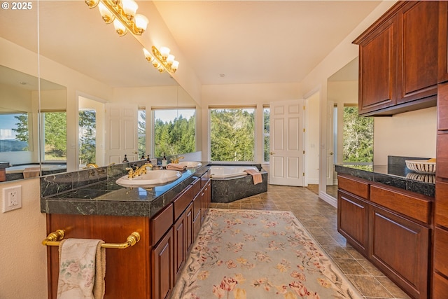 bathroom featuring an inviting chandelier, vanity, and tiled tub