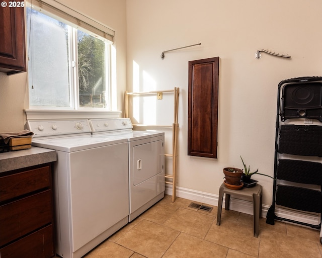 laundry area featuring light tile patterned floors, washer and clothes dryer, and cabinets