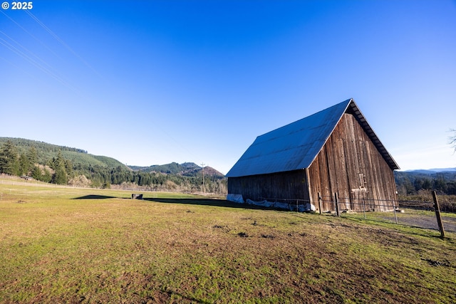 view of outbuilding featuring a rural view, a mountain view, and a yard