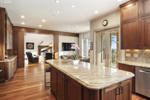 kitchen featuring a kitchen island, tasteful backsplash, dishwasher, and light stone countertops