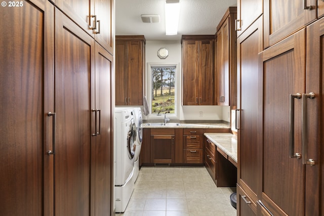 laundry area featuring washing machine and dryer, cabinets, and sink