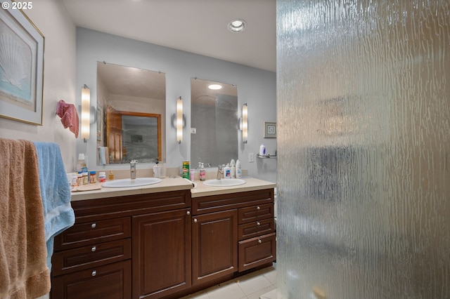 bathroom featuring tile patterned floors, an enclosed shower, double vanity, and a sink