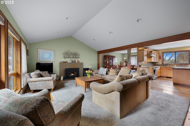 living room featuring a glass covered fireplace, recessed lighting, and lofted ceiling