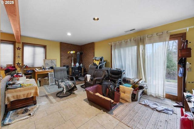 tiled living area featuring a wood stove, recessed lighting, and visible vents