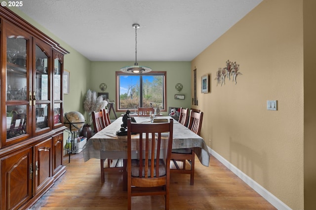 dining space featuring baseboards and light wood-style flooring