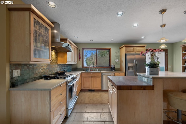 kitchen with a sink, decorative backsplash, appliances with stainless steel finishes, a kitchen bar, and wall chimney range hood