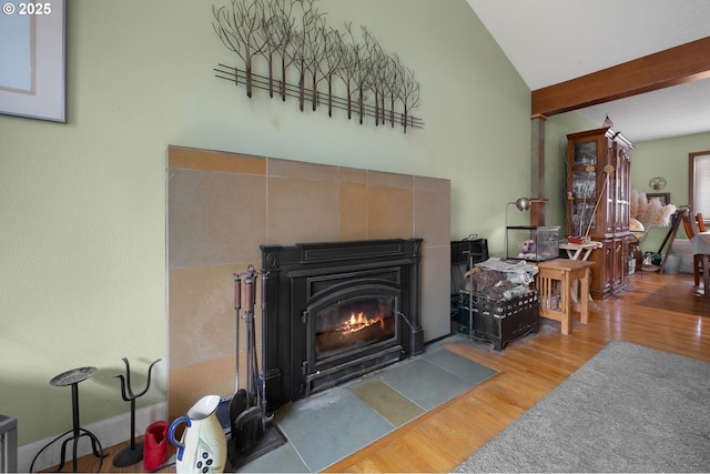 living area with lofted ceiling with beams, a fireplace with flush hearth, and wood finished floors