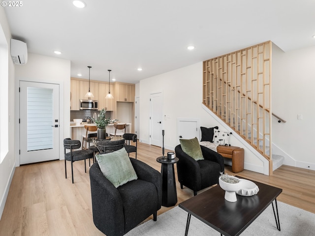 living area with a wall mounted air conditioner, recessed lighting, light wood finished floors, baseboards, and stairs