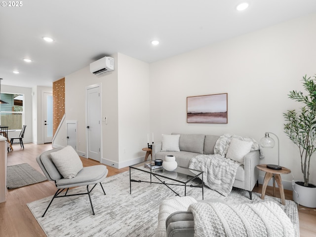 living area featuring a wall mounted air conditioner, baseboards, recessed lighting, and light wood finished floors