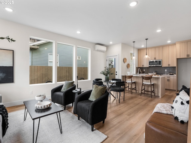 living area featuring baseboards, recessed lighting, an AC wall unit, and light wood-style floors