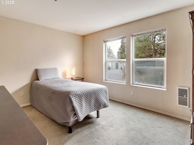 bedroom featuring heating unit and light colored carpet