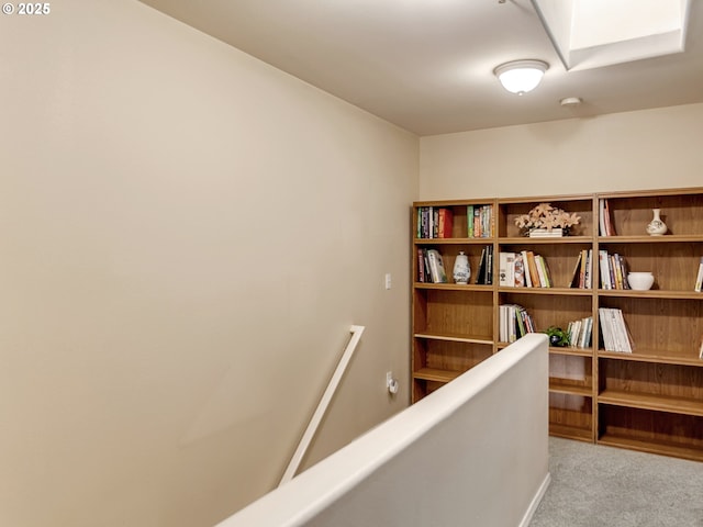 hallway with a skylight and light colored carpet