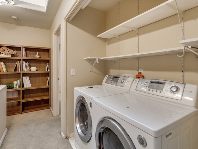 laundry room featuring light colored carpet, washing machine and clothes dryer, and a skylight