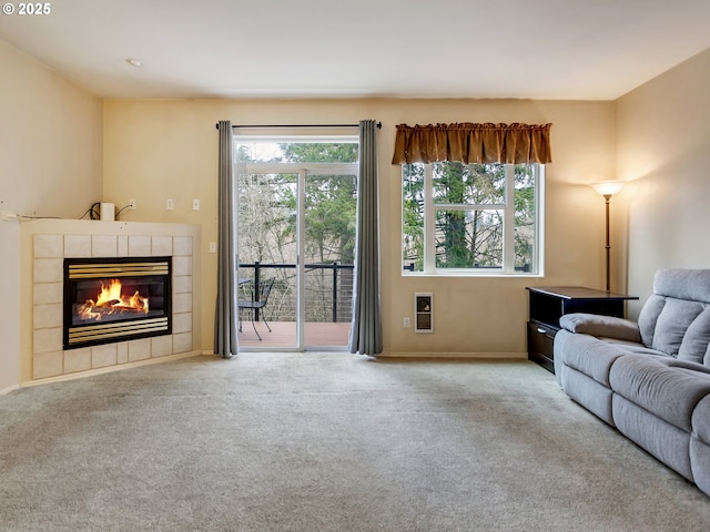 living room with light colored carpet, plenty of natural light, and a tile fireplace