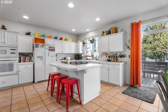 kitchen with tile countertops, white cabinets, white appliances, and a kitchen island