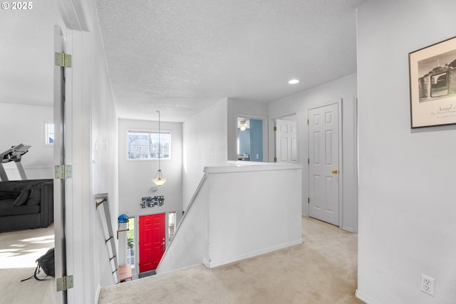 corridor featuring light carpet and a textured ceiling