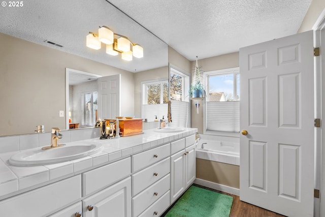 bathroom featuring a tub, plenty of natural light, vanity, and a textured ceiling