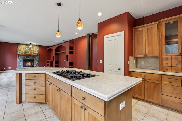 kitchen featuring light tile patterned floors, a kitchen island, open floor plan, black gas cooktop, and pendant lighting