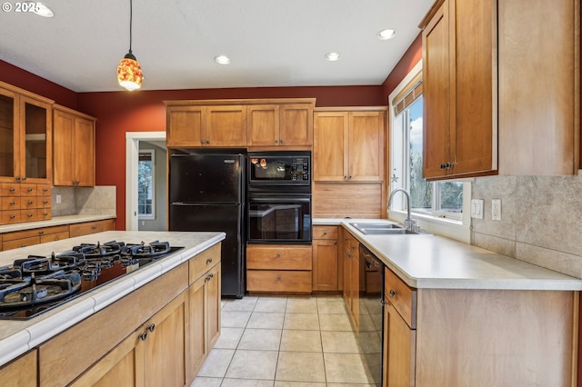 kitchen with pendant lighting, light countertops, a sink, and black appliances