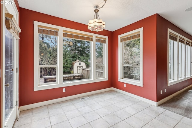 unfurnished dining area with a chandelier, light tile patterned floors, visible vents, and baseboards