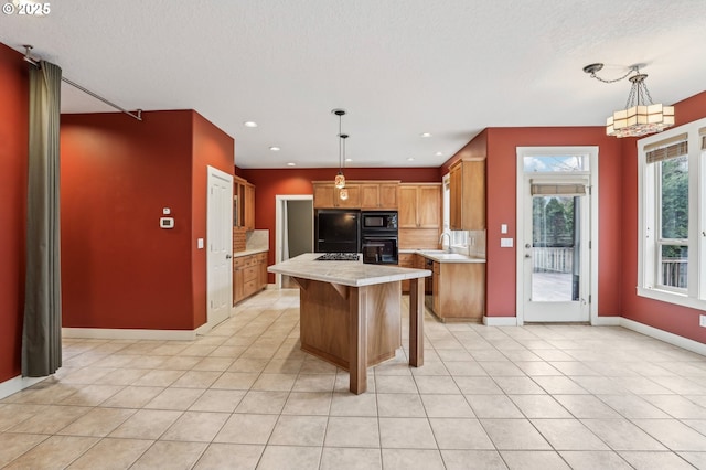 kitchen featuring hanging light fixtures, black appliances, a kitchen island, and light countertops