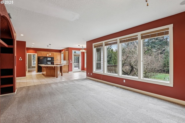 unfurnished living room with light tile patterned floors, a textured ceiling, light carpet, visible vents, and baseboards