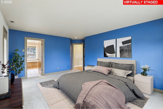 bedroom with ensuite bath, carpet flooring, visible vents, and baseboards