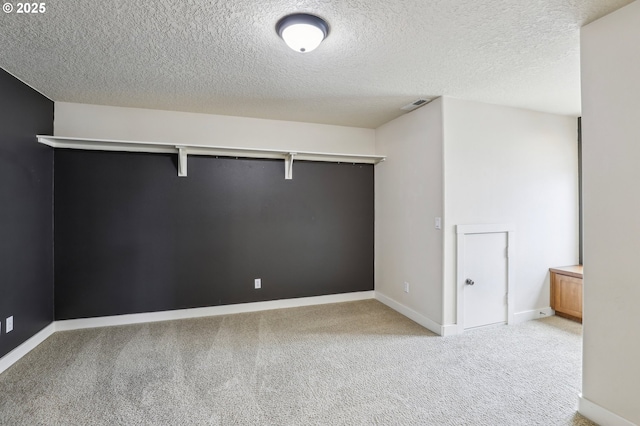 spare room featuring light carpet, baseboards, visible vents, and a textured ceiling