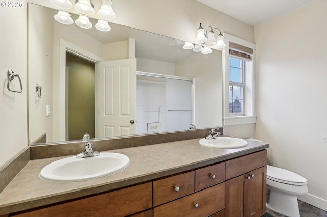 bathroom featuring double vanity, a shower stall, toilet, and a sink