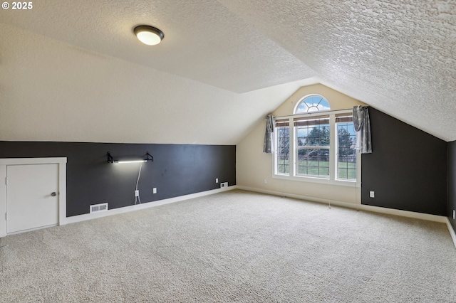 additional living space with lofted ceiling, carpet flooring, visible vents, and baseboards