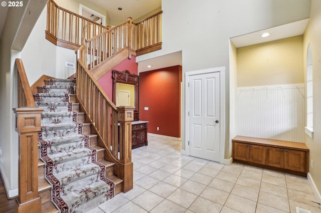 stairway featuring recessed lighting, a towering ceiling, wainscoting, tile patterned flooring, and baseboards