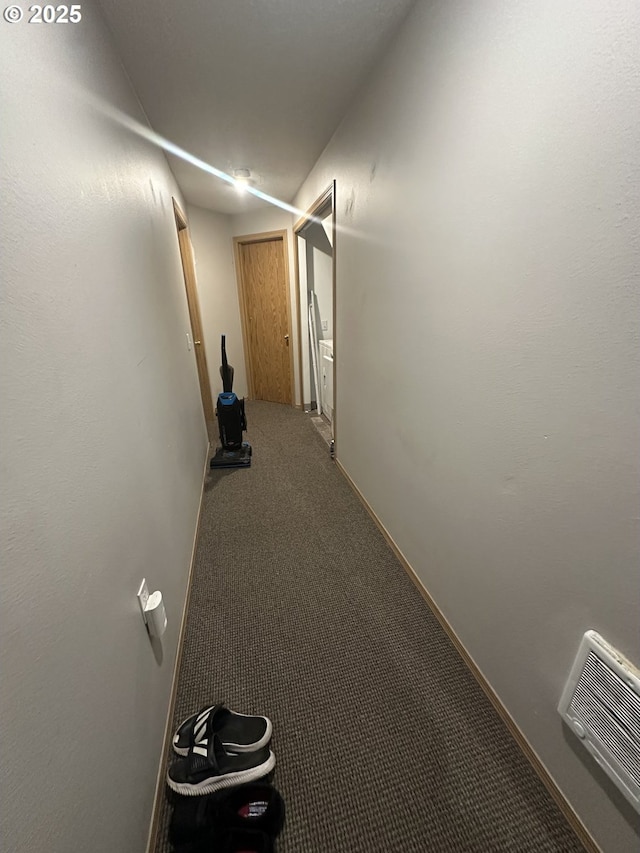 hallway featuring carpet floors, baseboards, and visible vents