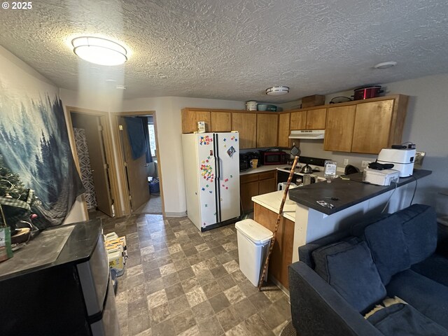 kitchen with brown cabinetry, white appliances, a peninsula, and under cabinet range hood