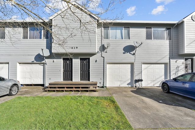 view of property featuring a garage, driveway, and a front lawn