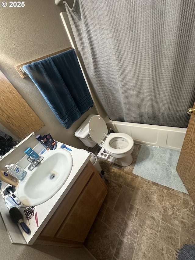 full bath with toilet, a textured wall, shower / bath combo, and vanity