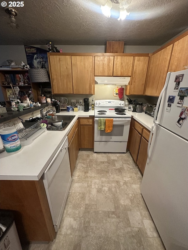 kitchen with light countertops, a sink, a textured ceiling, white appliances, and under cabinet range hood