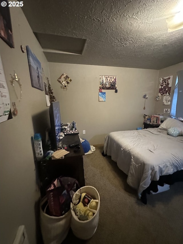 bedroom with a textured ceiling, carpet, and attic access