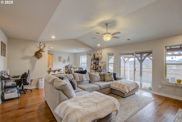 living room featuring ceiling fan, lofted ceiling, a textured ceiling, and hardwood / wood-style flooring