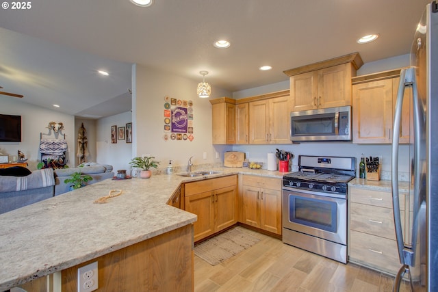 kitchen featuring appliances with stainless steel finishes, light wood-type flooring, light stone countertops, sink, and kitchen peninsula