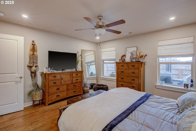 bedroom featuring light wood-type flooring, ceiling fan, and multiple windows