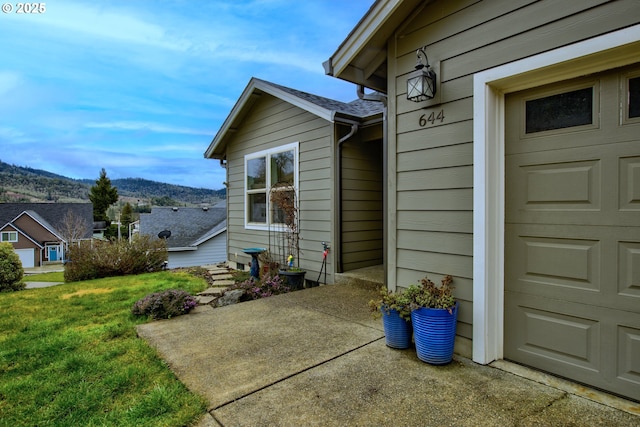 view of side of property with a patio, a lawn, and a mountain view