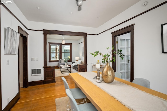 dining space with light wood-type flooring, decorative columns, baseboards, and heating unit