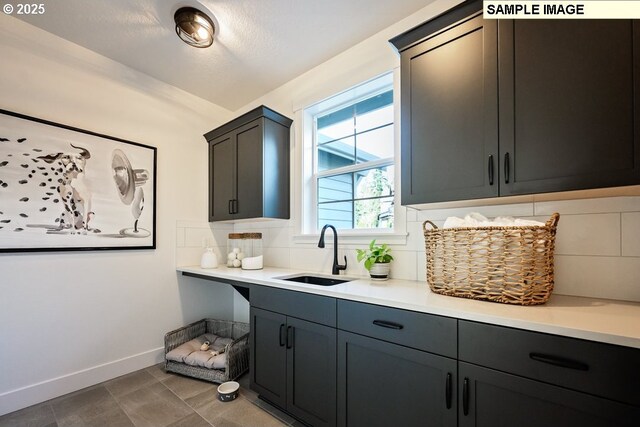 kitchen with baseboards, a sink, light countertops, and tasteful backsplash